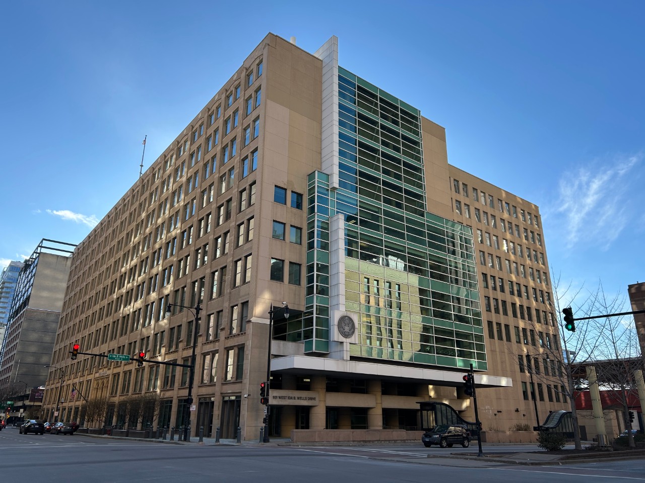Exterior of the office building that houses the Chicago Passport Agency. It is a rectangular building with rows of windows. It sits behind a street with a crosswalk.
