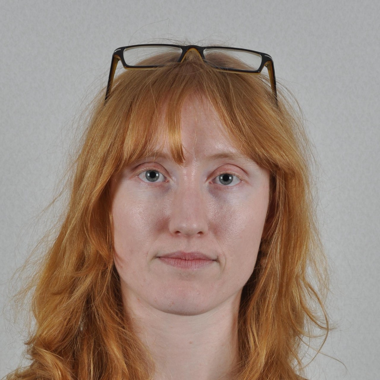 Photo of a woman with her glasses resting on her head. 