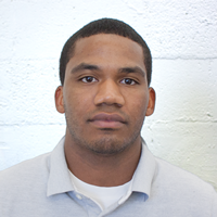 Photo of a man against a white brick wall.