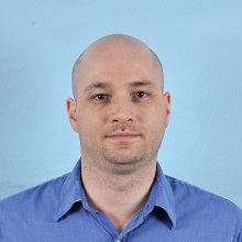 Photo of a man against a blue background.