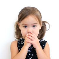 Photo of a little girl covering her mouth with her hand.