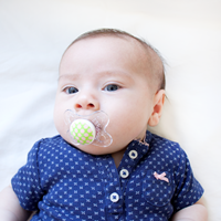 Photo of a baby with a pacifier in its mouth.